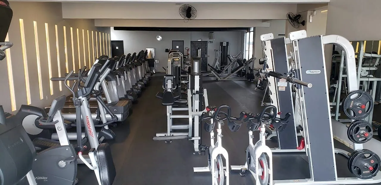 Aparelhos de cardio enfileirados ao lado das máquinas de musculação