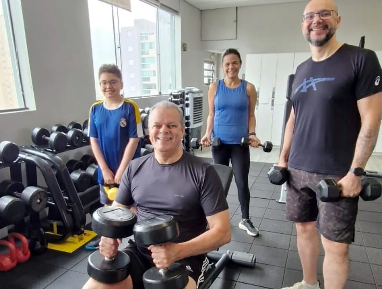 A mesma família com halteres e kettlebell no salão de pesos livres